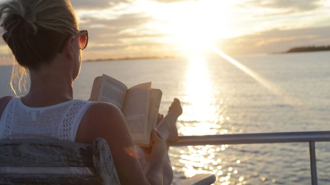 Vrouw leest boek op cruise dek schip