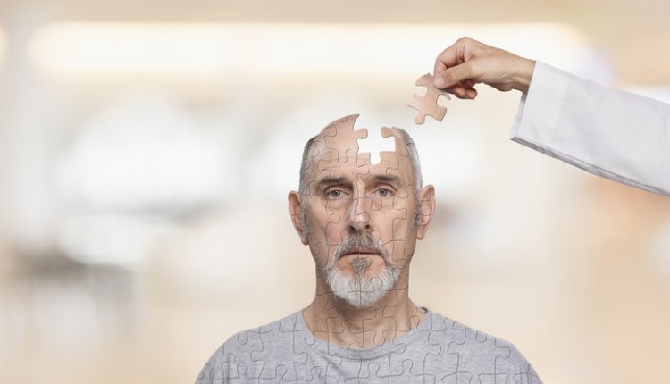 Man met hoofd waaruit een puzzelstukje is weggenomen, dat een hand met witte jas weer toevoegt. Senior.