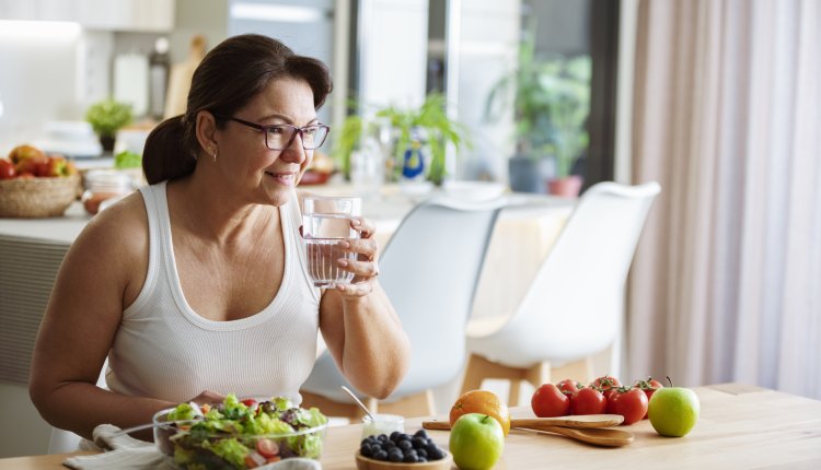 Vrouw eet en drinkt zomer fruit in de keuken