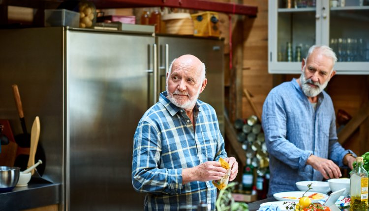 Oudere mannen zijn vrienden van elkaar samen koken in de keuken