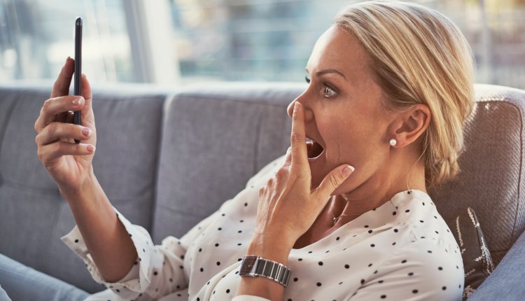 Vrouw is verbaasd bezig met haar mobiele telefoon