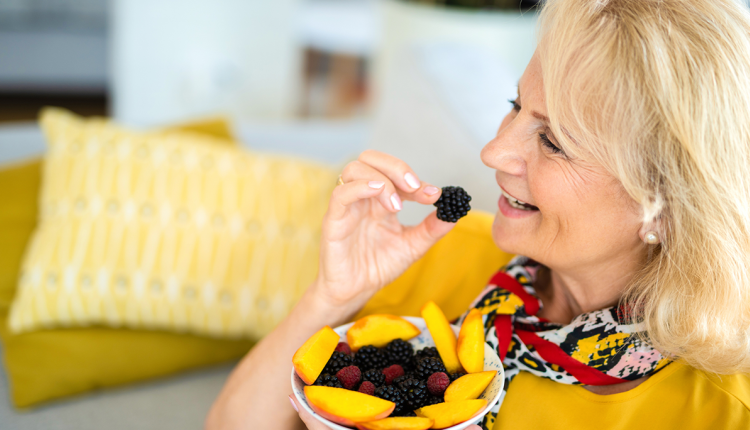 Vrouw eet fruit op de bank