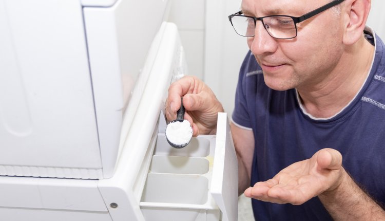 Wasmachine man doet poeder in vakje