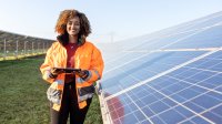 Vrouw staat naast zonnepanelen in een weiland