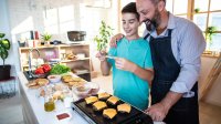 Hamburgers bakken vader en zoon in de keuken met kaas