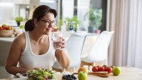 Vrouw eet en drinkt zomer fruit in de keuken