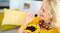 Vrouw eet fruit op de bank