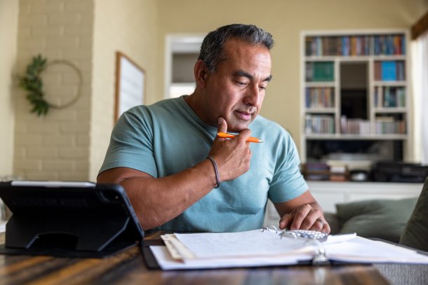 Man doet belastingaangifte aan zijn bureau, peinzende blik