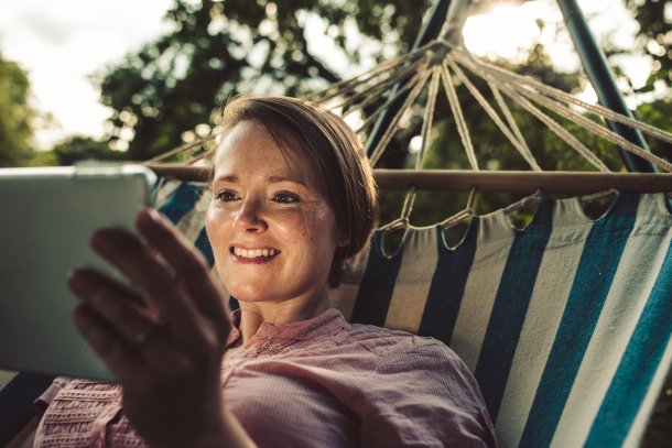 Knappe vrouw in hangmat geniet met tablet