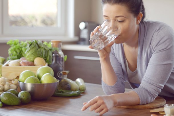 Vrouw doet aan bulkdrinken in de keuken met glas water